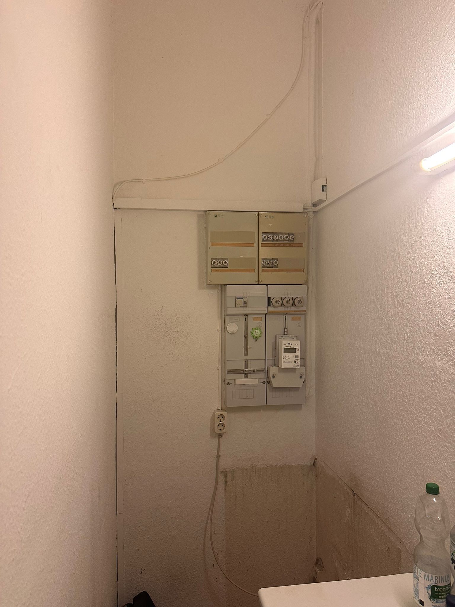 Elektroverteilung vor der Sanierung: Zählerschrank und Sicherungskasten offen an der Wand, Leitungen auf Putz bis unter die Decke geführt.