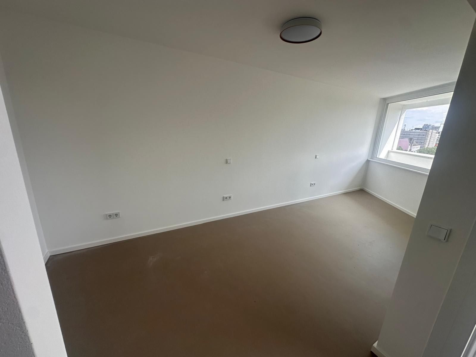 Fertiges Schlafzimmer mit hellem Boden, weißen Wänden, Deckenleuchte und einem Fenster in der Nische, Steckdosen und Schalter gesetzt.